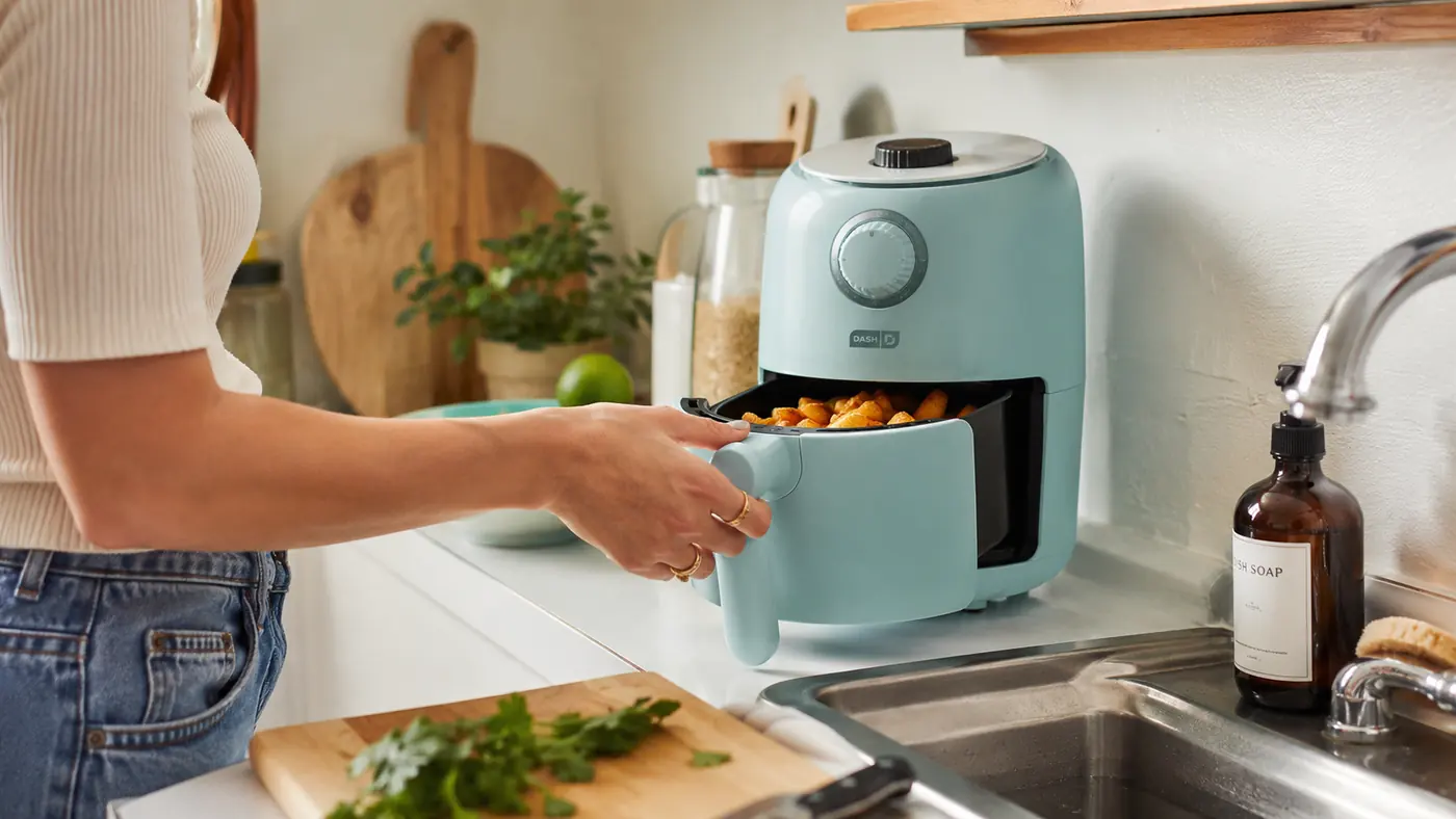 Dash Tasti-Crisp Air Fryer sitting on a narrow apartment counter next to a cutting board