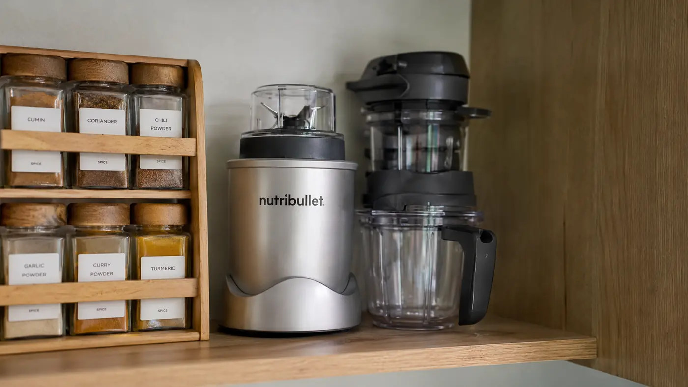 Magic Bullet blender parts nested together for storage on a narrow kitchen shelf